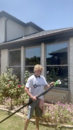 Technician scrubbing exterior glass with a water-fed pole