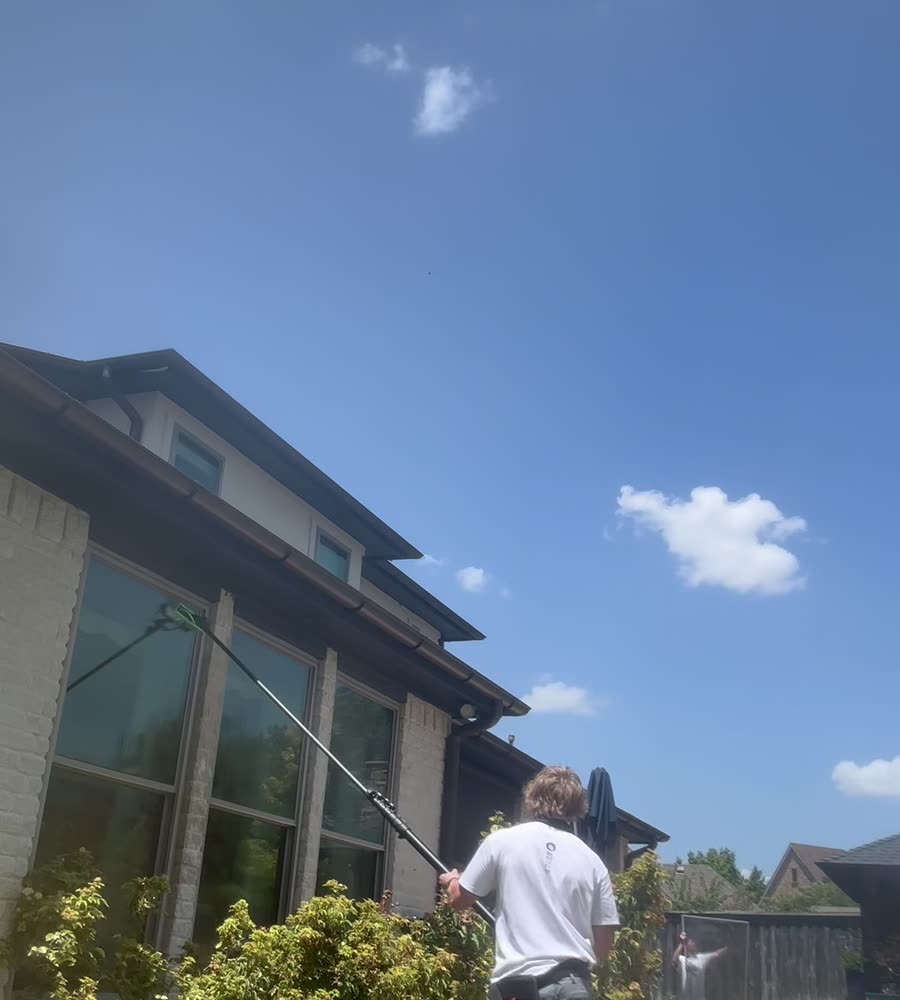 Technician reaching high glass with a water-fed pole