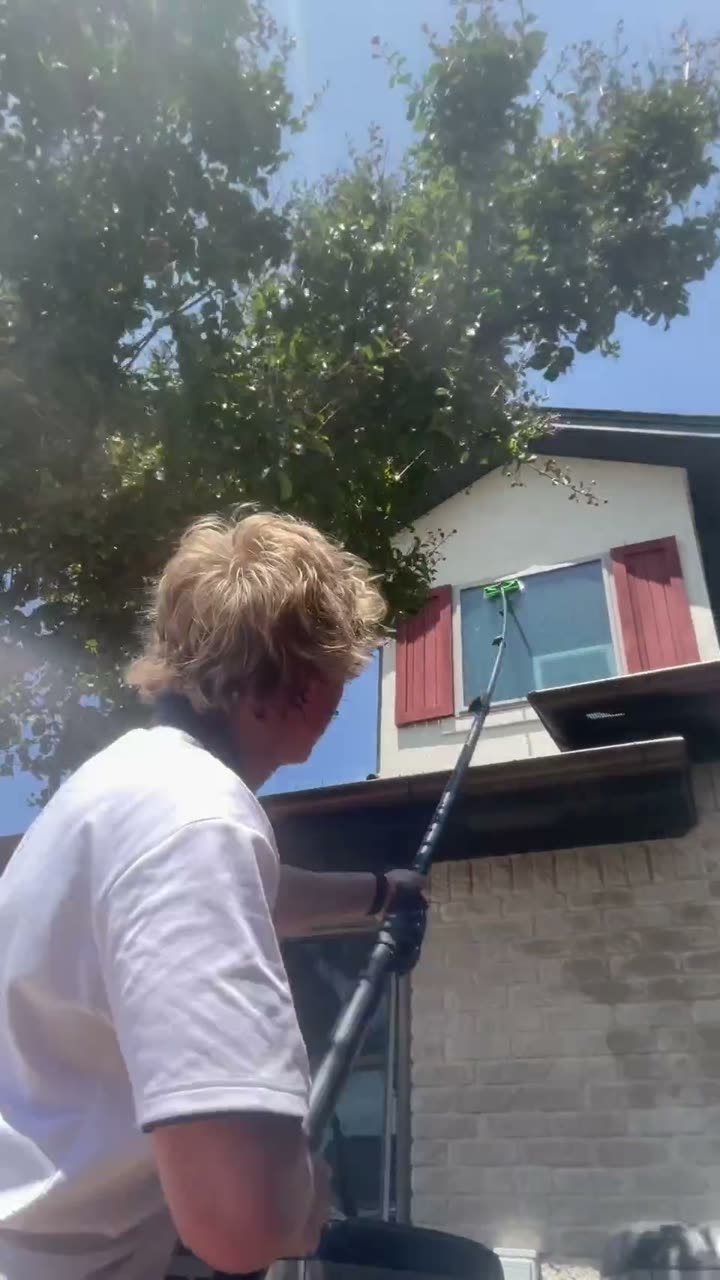Berry Bros technician cleaning second-story windows with a water-fed pole